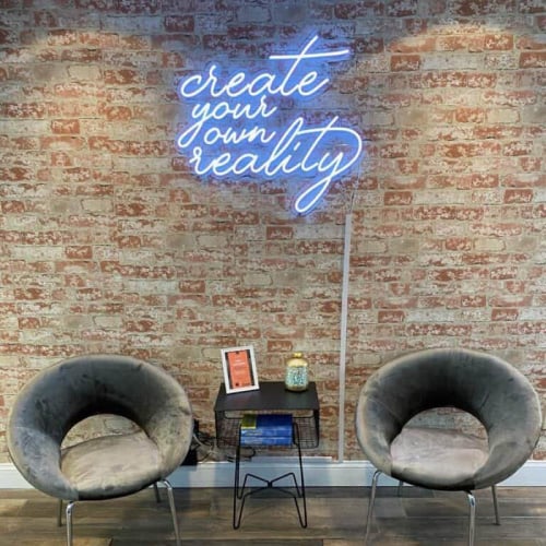 2 chairs in detox center in front of neon sign reading "create your own reality"
