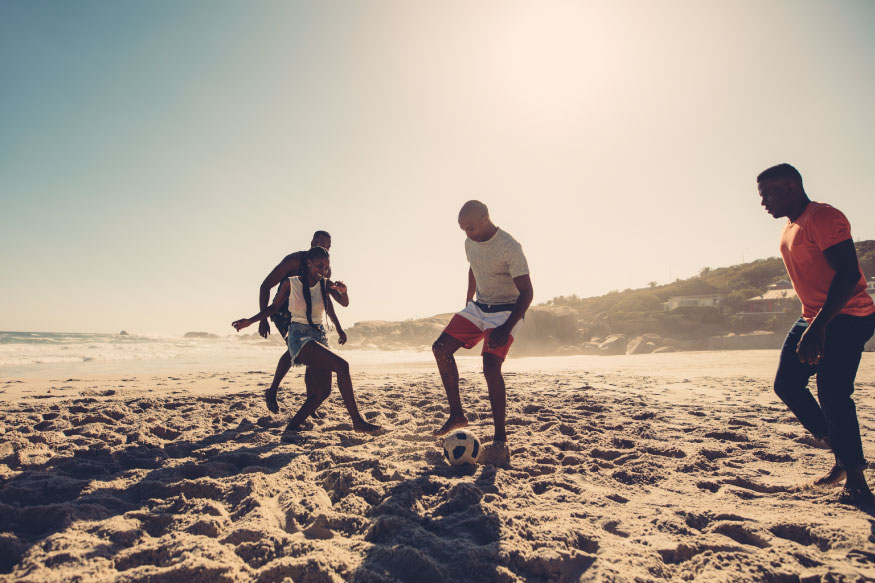 friends playing soccer on sunny beach in florida as part of christian rehab