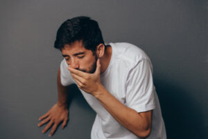 man covering his mouth trying not to vomit
