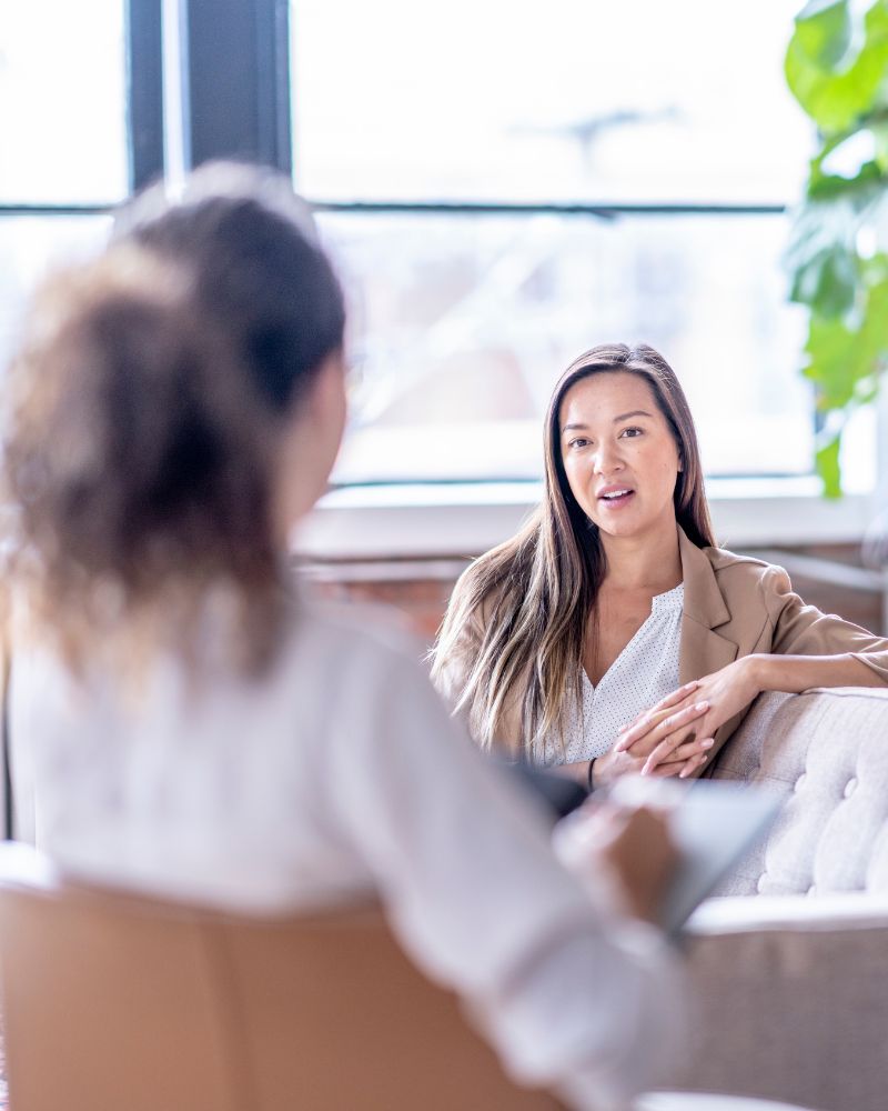a woman sits with a therapist. addiction treatment help all in solutions