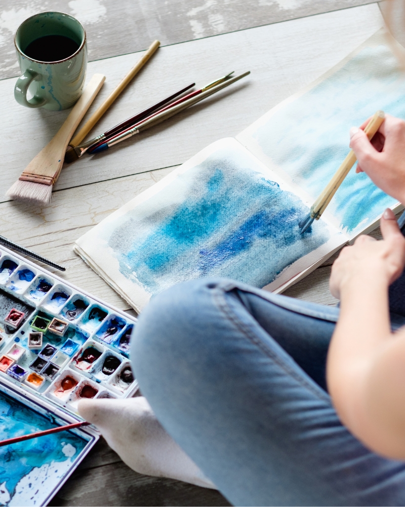 woman painting on the ground; all in solutions art therapy addiction treatment