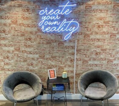 2 chairs in detox center in front of neon sign reading "create your own reality"